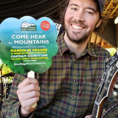 Musician smiles with promotional fan at Merlefest